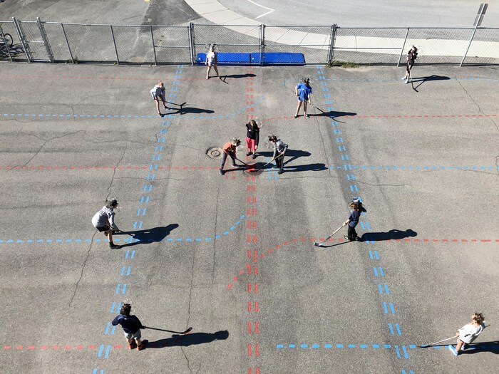 Des élèves jouent au hockey dans une cour d'école.