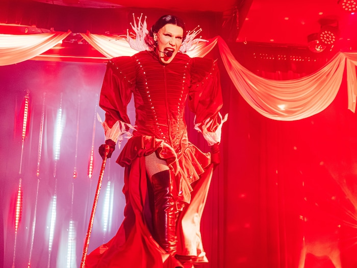 Une personne en rouge est sur scène. 