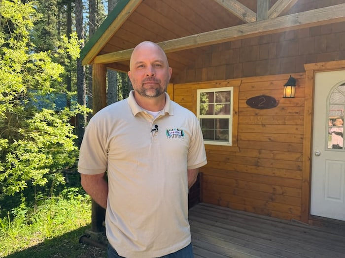 Jon Offert est devant un chalet en bois.
