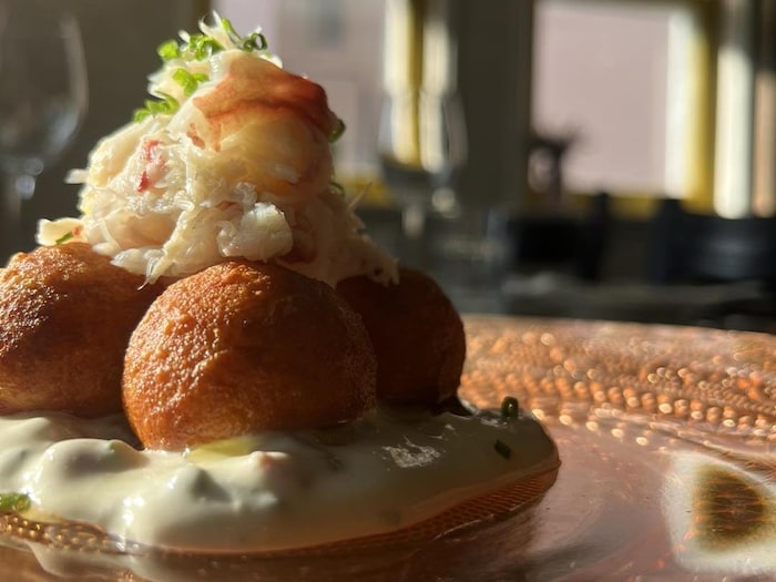 Une assiette nappée de sauce ranch où reposent des gnudis surmontés de chair de crabe des neiges.