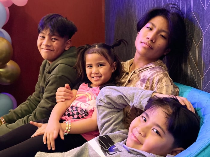 Une photo de famille avec trois enfants sur les genoux d'un adolescent.