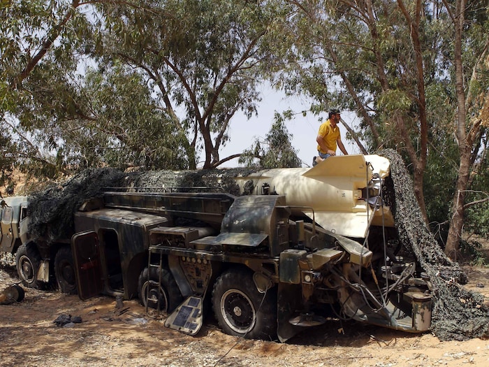 Un homme est agenouillé sur un missile transporté par un camion dans la forêt.