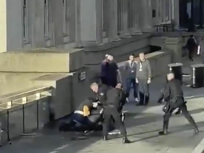 Un homme est étendu et maintenu au sol par des policiers armés.
