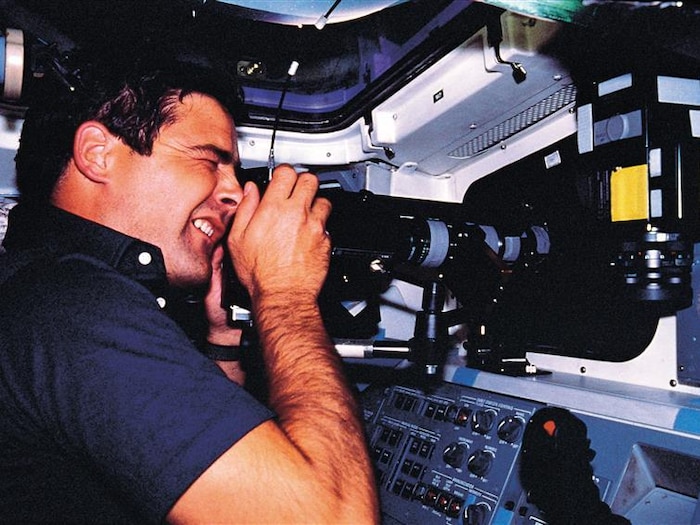 L'astronaute canadien Marc Garneau menant une expérience à bord de la navette Challenger.