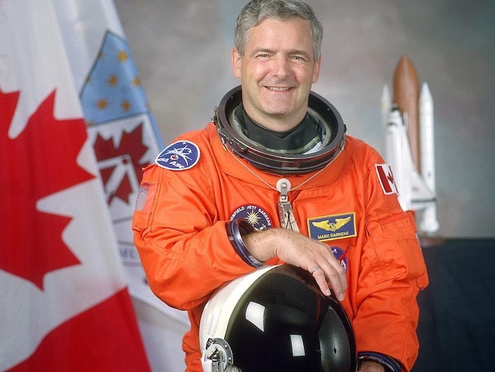 L'astronaute Marc Garneau devant le drapeau canadien.