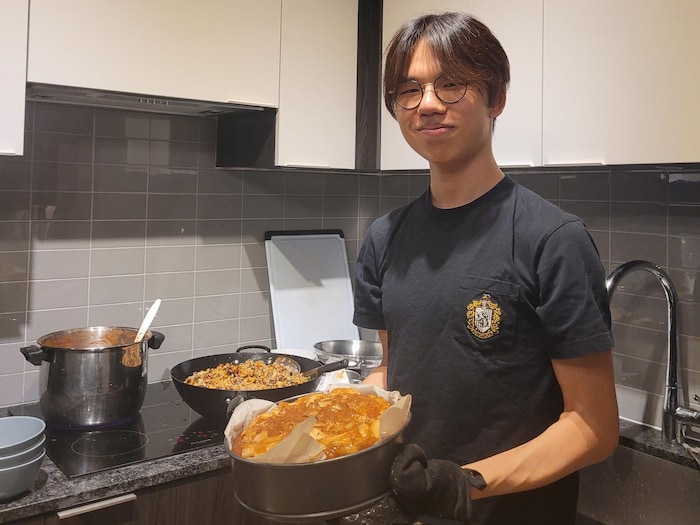 Marcus Yang tient un plat dans ses mains et sourit face à la caméra.
