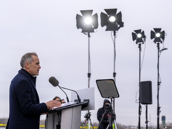 Le chef libéral Mark Carney en point de presse devant des projecteurs.