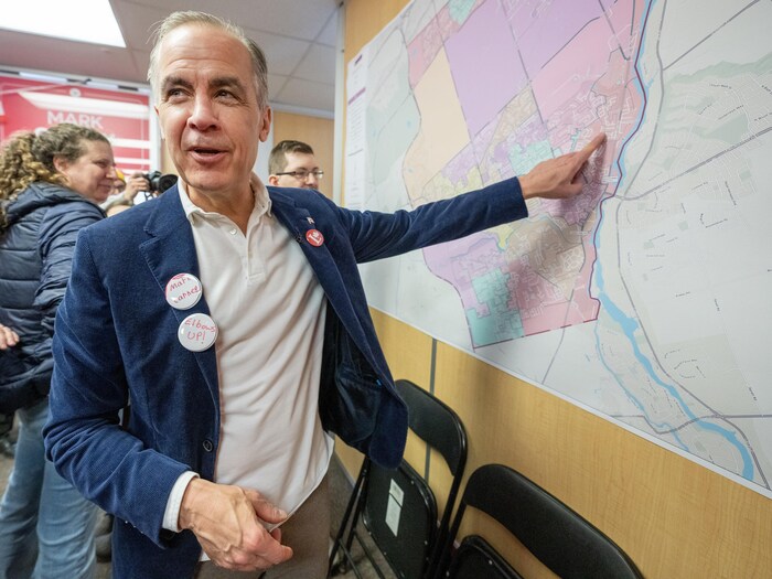 Le chef libéral Mark Carney examine une carte de sa circonscription à son bureau de campagne à Nepean, en Ontario, le samedi 29 mars 2025.