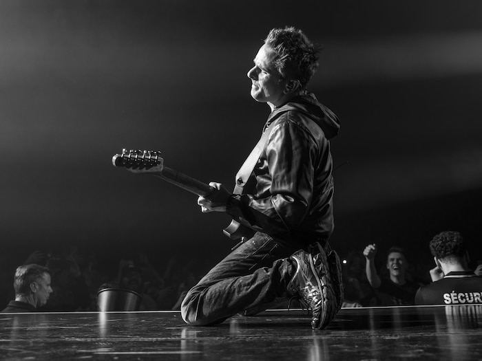 Matthew Bellamy joue de la guitare à genoux sur la scène.