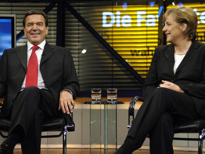 Gerhard Schroeder et Angela Merkel sont assis et sourient.
