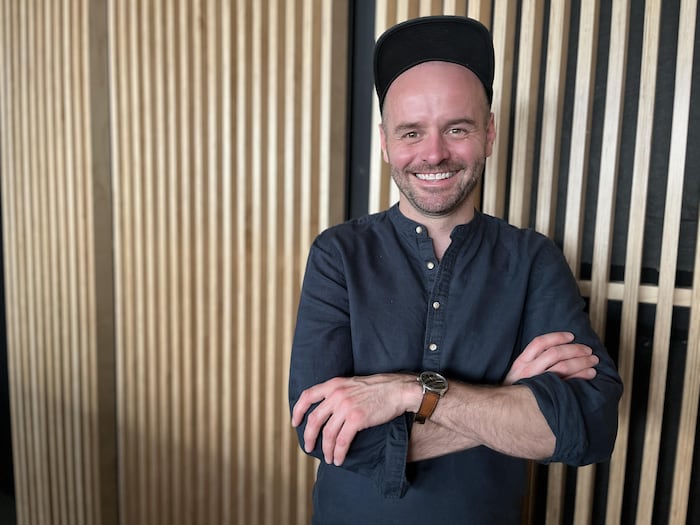 Michel-Maxime Legault pose dans les locaux du Centre du Théâtre d'Aujourd'hui, souriant.
