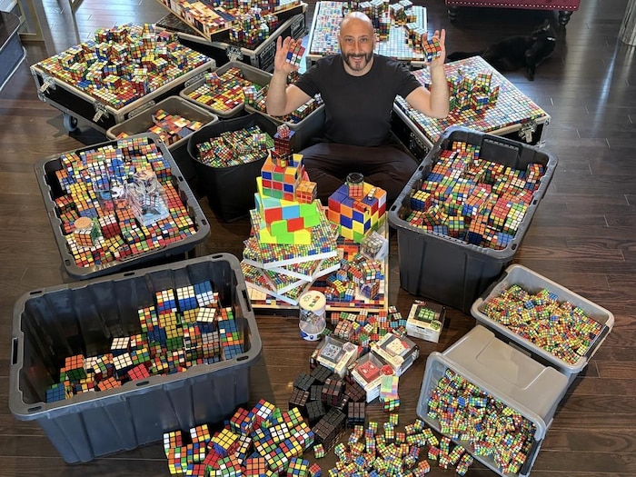 Mikael Taiebest assis et entourré de cubes Rubik.