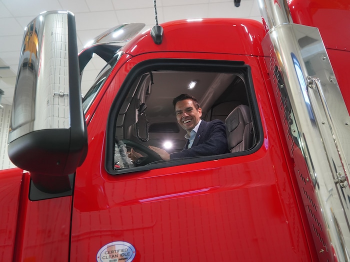 Charles Milliard souriant au volant d'un camion.