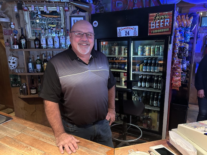 Un homme debout derrière un bar.