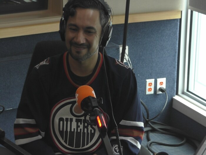 Un partisan assis dans un studio radio portant un chandail bleu avec le logo des Oilers d'Edmonton le 24 juin 2024.
