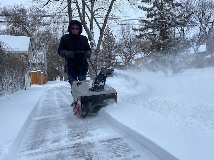 Un homme déblaie un trottoir à Saskatoon. Il est tombé environ 15 cm de neige mercredi dans la ville. Le 10 janvier 2024.