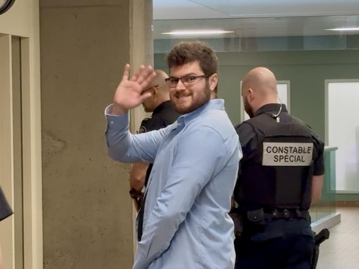 Le jeune homme envoie la main avec un sourire au photographe.