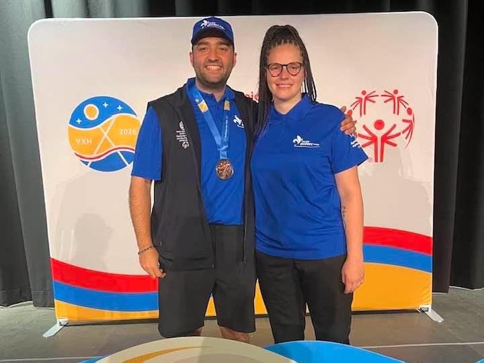 Un homme et une femme vêtus de vêtements de sport bleus posent côte à côte en souriant.