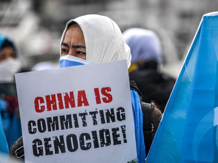 Une femme tient une affiche dénonçant le « génocide ouïghour ».