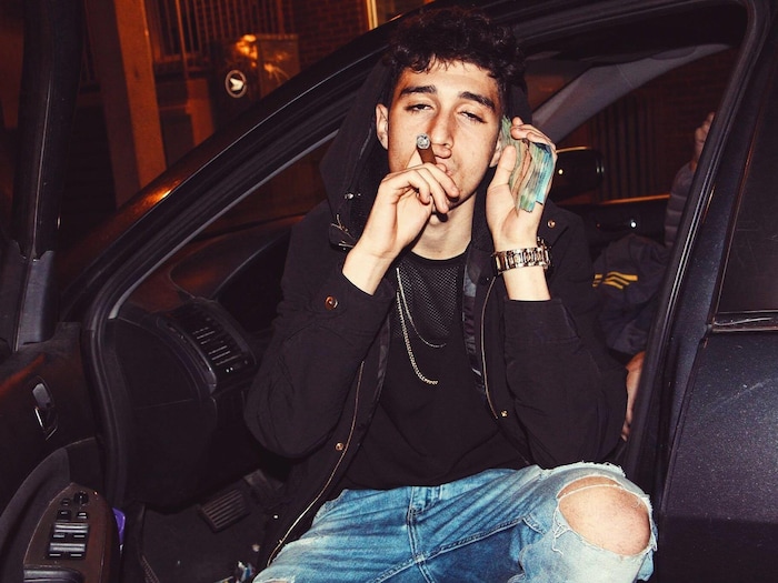 Cigare au bec dans une main, liasse d'argent dans l'autre, il pose dans une voiture