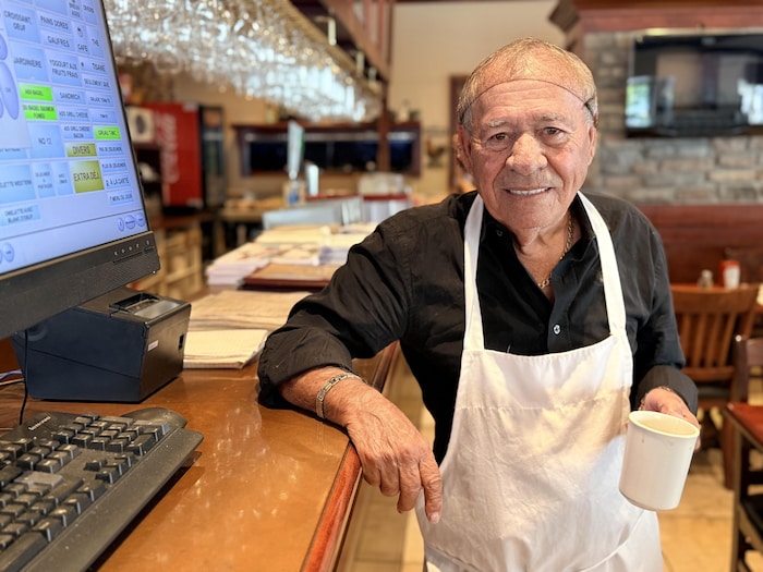 L'homme pose avec son filet sur la tête, son tablier et sa tasse à café.