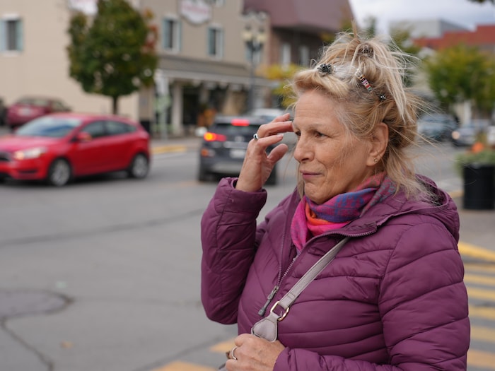 Femme âgée qui regarde les voitures qui passent devant elle.