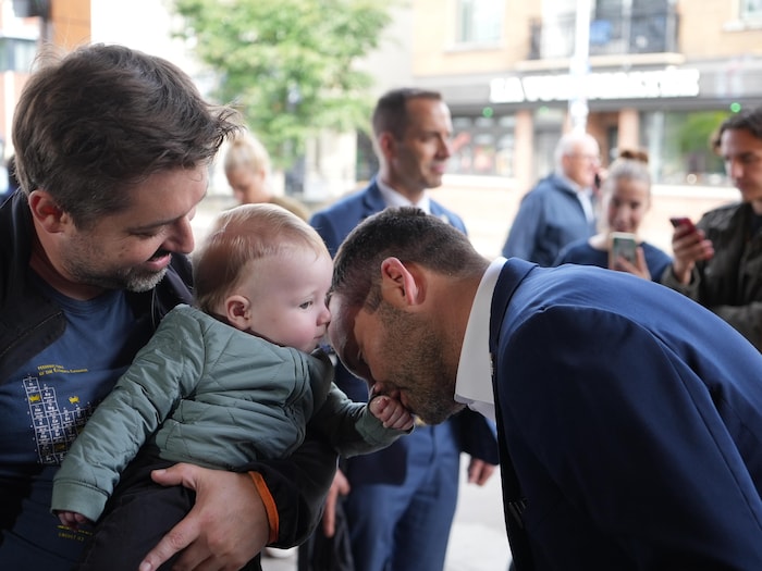 Paul St-Pierre Plamondon embrasse la main d'un bébé.