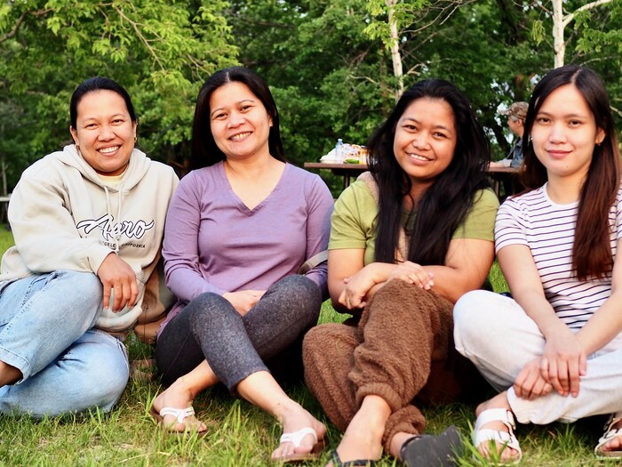 Des femmes sont assises en tailleur dans l'herbe.