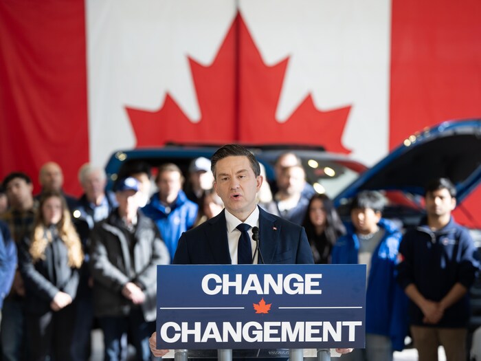 Pierre Poilievre devant une voiture neuve.