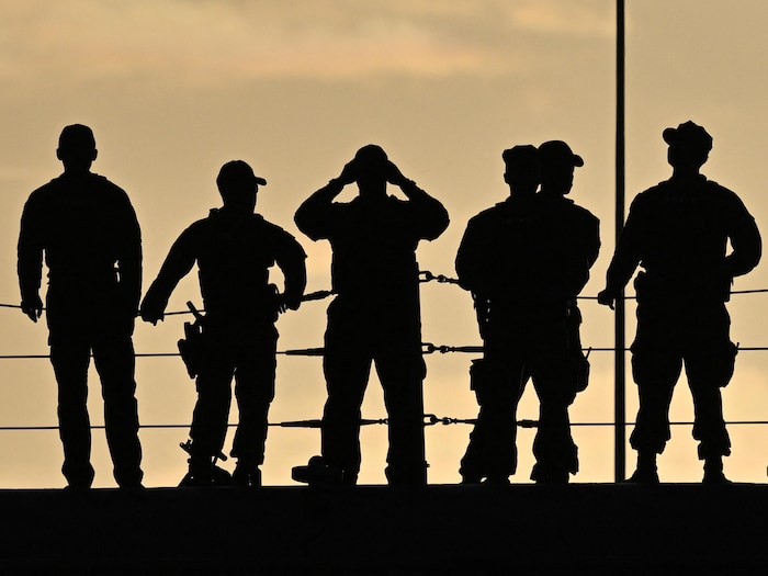 Les silhouettes de six militaires sur le pont d'un navire.