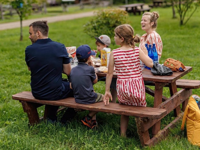 Paul St-Pierre Plamondon assis à une table de pique-nique avec sa conjointe et ses trois enfants.