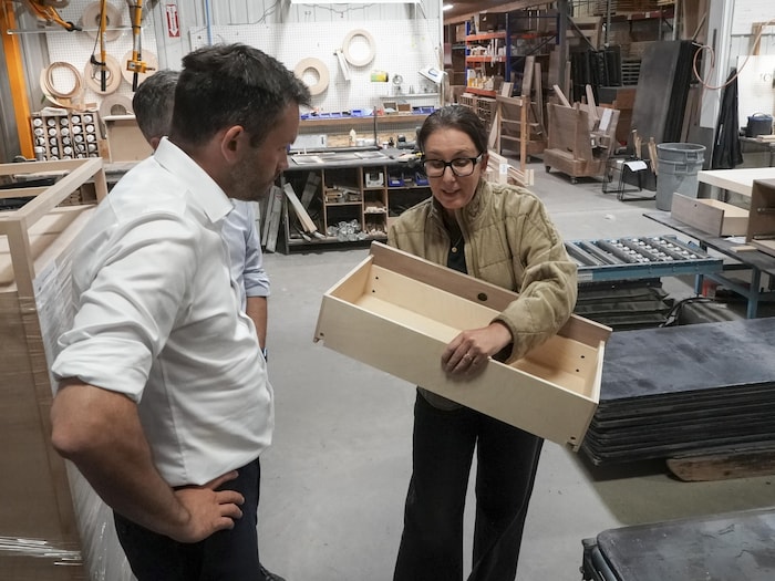 M. St-Pierre Plamondon regarde une employée en train d'assembler un meuble.