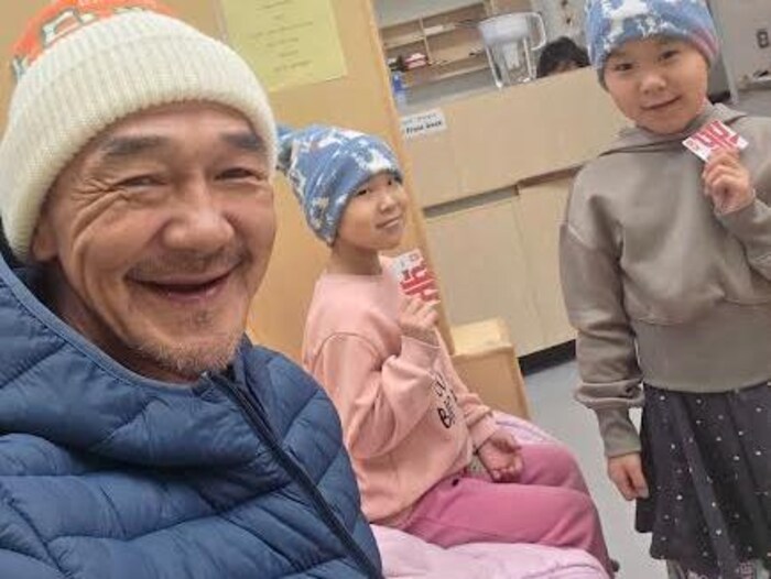 Un homme prend une photo de lui avec deux enfants, dans un centre de santé.