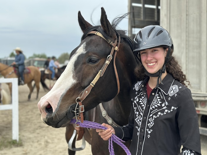 Une jeune femme pose avec son cheval.