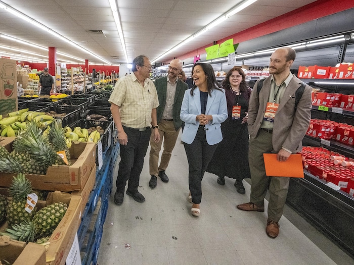 Ruba Ghazal, en veston bleu, et Sol Zanetti discutent avec un homme dans une allée d'épicerie.