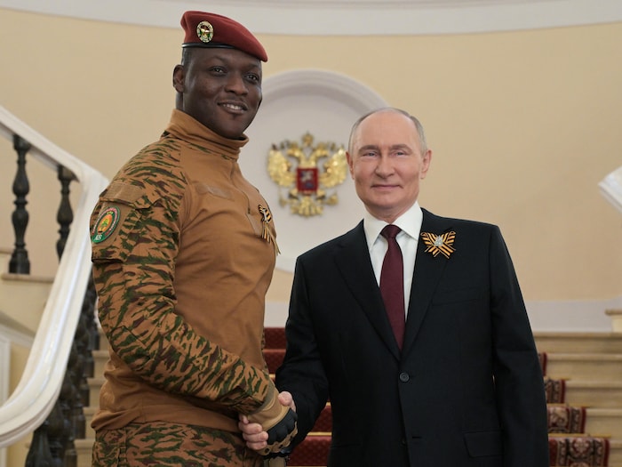 Vladimir Poutine pose au pied d'un escalier alors qu'il serre la main d'Ibrahim Traore.