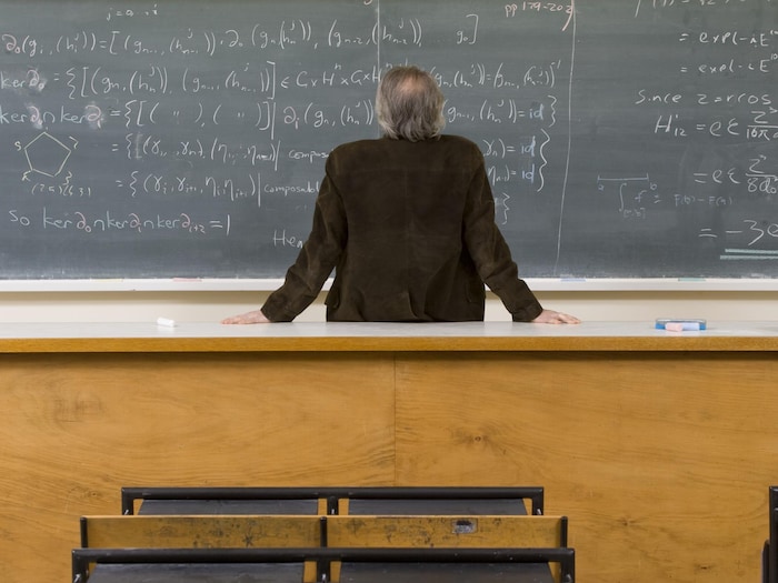 Un professeur regarde un tableau noir.
