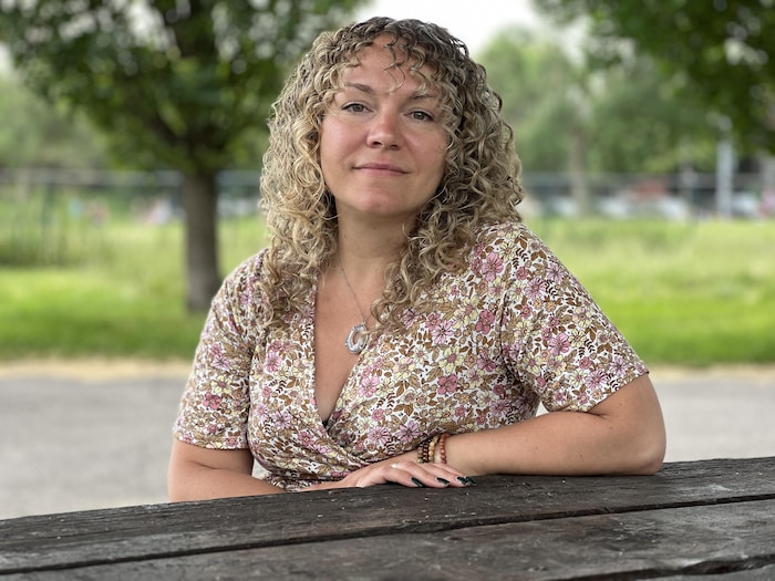 Carolane nCampeau assise à une table de pique-nique dans un parc.