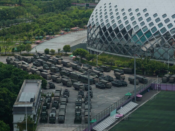 Des dizaines de véhicules sont stationnés près d'un stade.