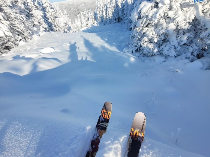 Les bouts d'une paire de ski sont visibles sur le flanc d'un montagne couverte de neige.