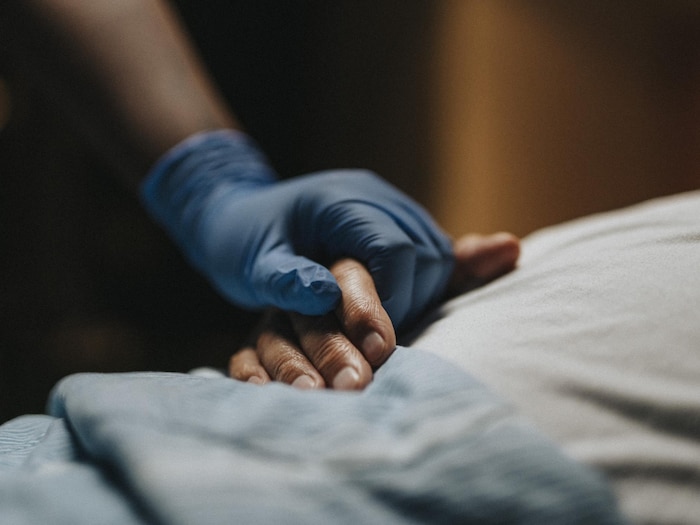 La main d'un professionnel de la santé tenant celle d'un patient.