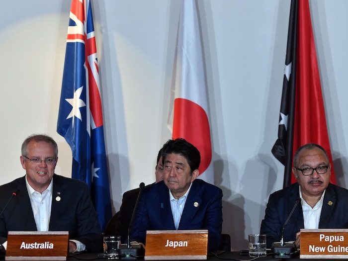 MM. Morrison, Abe et O'Neill sont assis devant des drapeaux de leurs pays respectifs.