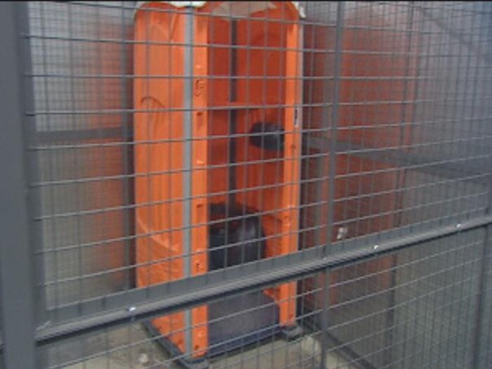 Une cage avec une toilette sans porte.