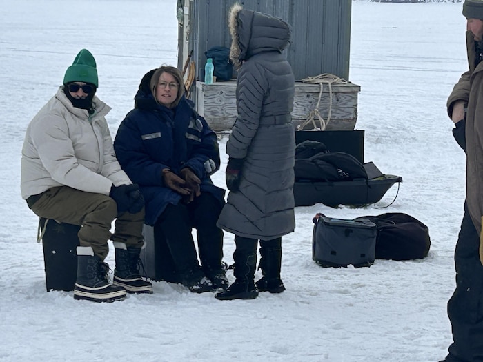 Trois personnes devant des cabanes.