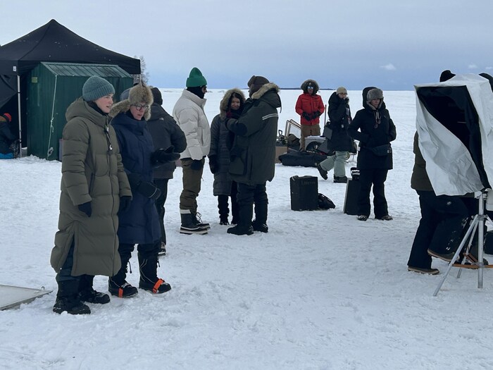Des gens sur la glace avec des cabanes à éperlans.