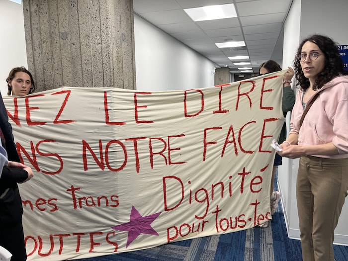 Trois femmes tiennent une banderole au complexe G.