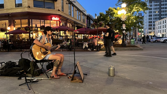 Un guitariste joue et chante dans une rue du marché By d'Ottawa, de nuit.