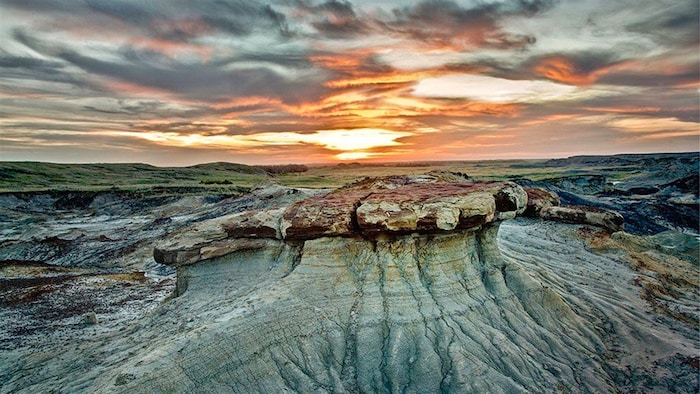 Une formation rocheuse d’une forme étrange devant un plateau et de basses collines désertiques