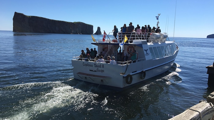 Un bateau rempli de touristes quitte un quai en direction d’une île