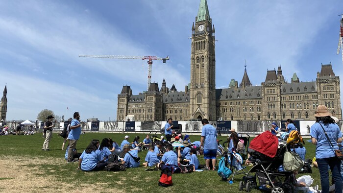 Des jeunes anti-avortement sont assis dans l'herbe devant le parlement d'Ottawa.